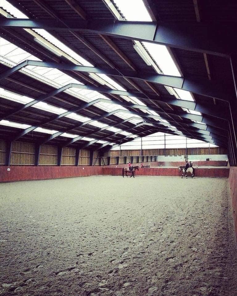 Ridehal hvor vi ser nogle ryttere, bagerst i billedet